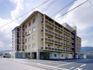 介護施設の建物外観。複数階の居室と1階の共用スペースを備えた近代的な施設棟
