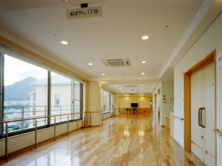 明るい共用廊下。大きな窓から山景が見え、床は光沢のある床材で統一されている。