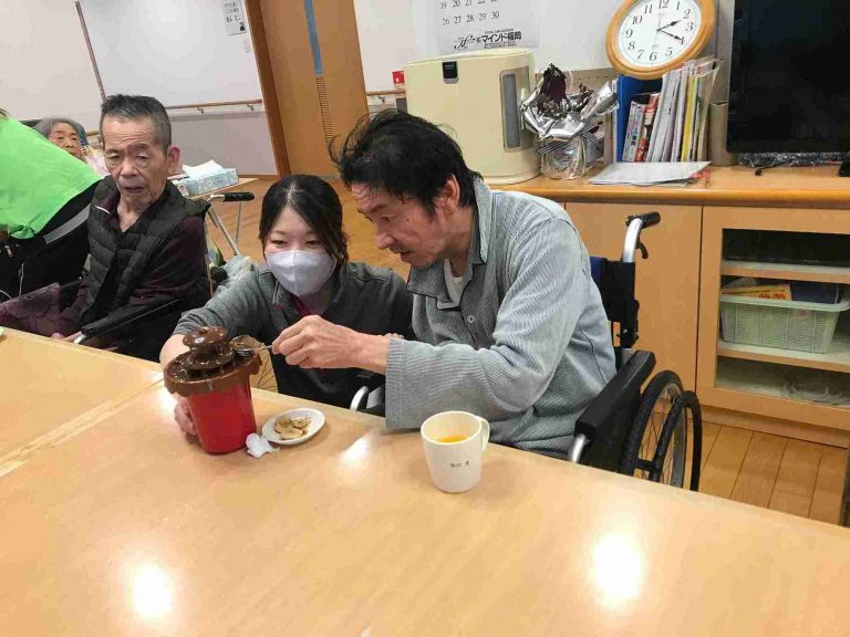 入居者がスタッフと一緒にお菓子を楽しむレクリエーション風景